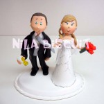 Bonecos do bolo de casamento com a noiva puxando o noivo pela gravata