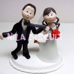 Bonecos do bolo de casamento com a noiva puxando o noivo pela gravata e com o pé levantado