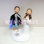 Bonecos do bolo de casamento com a noiva puxando o noivo pela gravata e noivo com prancha se durf