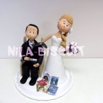 Bonecos do bolo de casamento com a noiva puxando pela gravata e noivo com notebook