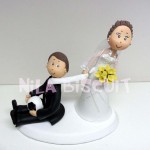 Bonecos do bolo de casamento com a noiva puxando pela gravata e noivo segurando bola de futebol