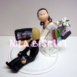 Bonequinhos do bolo de casamento com noivo assistindo jogo de futebol e noiva puxando ele