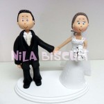 Bonequinhos do bolo de casamento com noivos de mãos dadas
