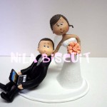 Noivinhos do bolo de casamento com a noiva puxando noivo pelo colarinho e o noivo segurando notebook