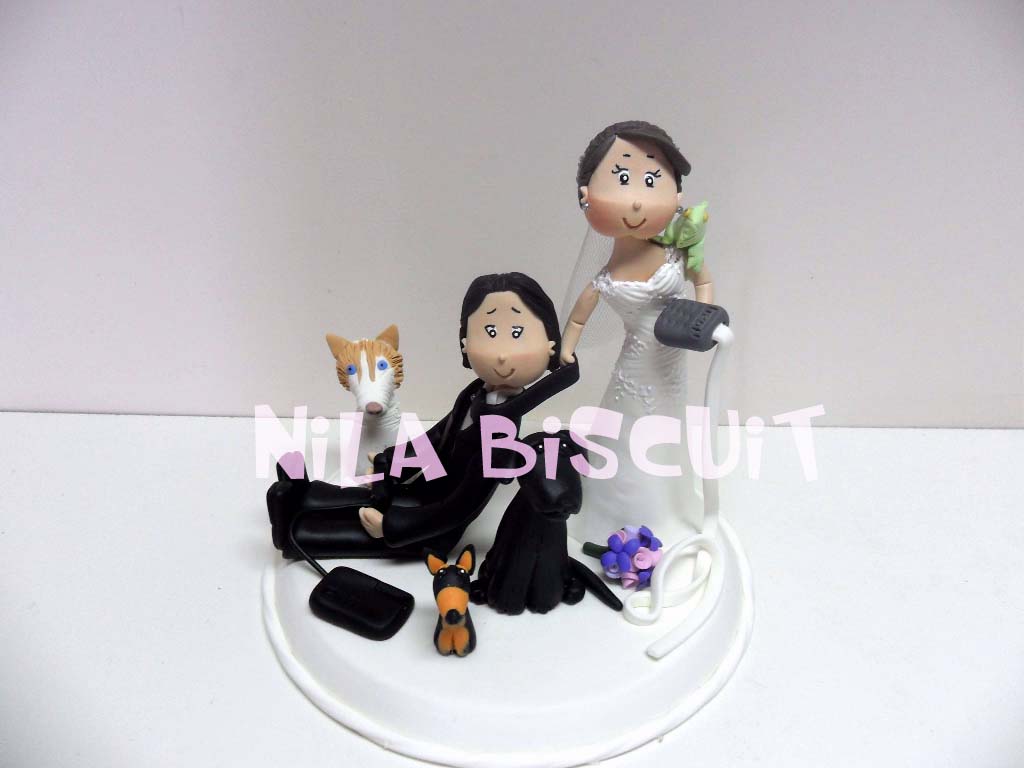 Bonecos do bolo de casamento com a noiva puxando pela gravata e com uma iguana no ombro