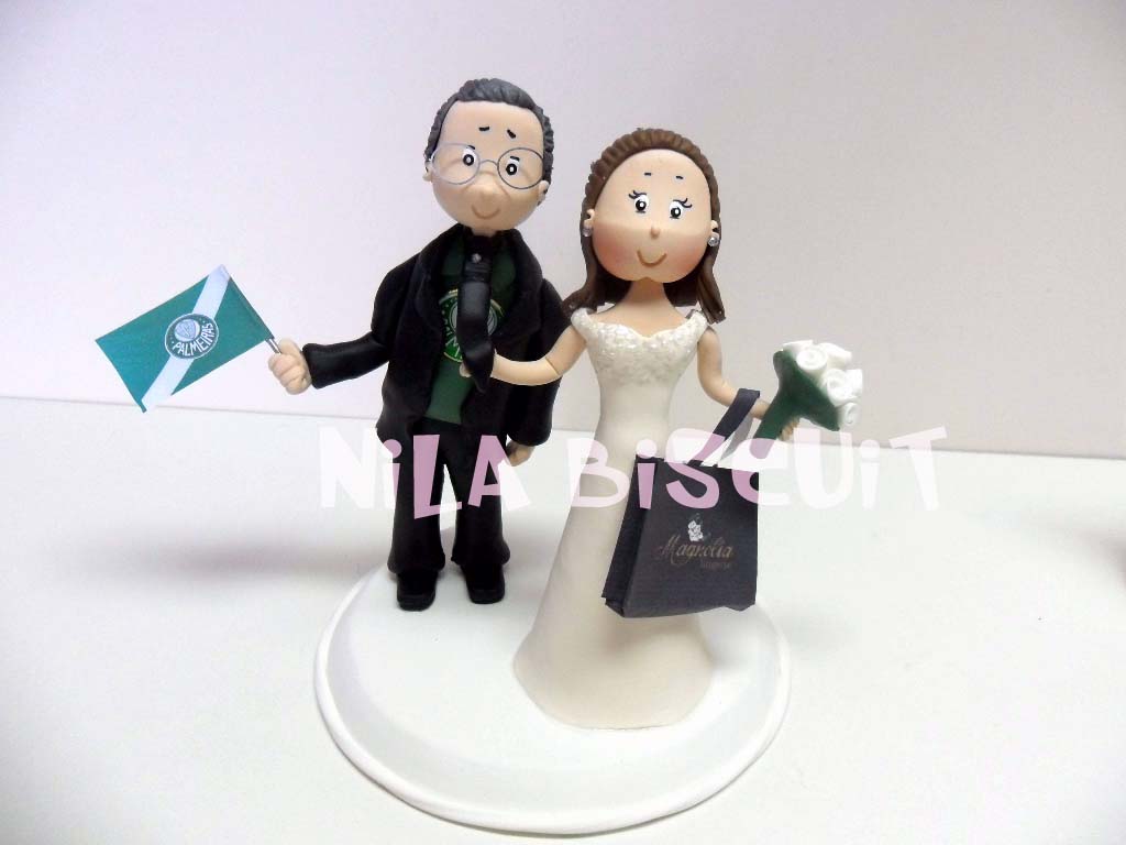 Bonecos do bolo de casamento com a noiva puxando pela gravata e segurando sacolas de compras