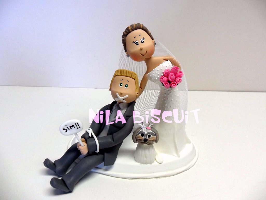 Bonequinhos do bolo de casamento com a noiva puxando o noivo amarrado pelo colarinho