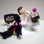 Bonequinhos do bolo de casamento com noivo jogando video game de futebol e noiva com sacolas de compras