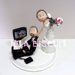 Bonequinhos do bolo de casamento com noivo jogando video game de futebol e noiva puxando