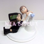Bonequinhos do bolo de casamento com noivo jogando video game de futebol e noiva puxando ele