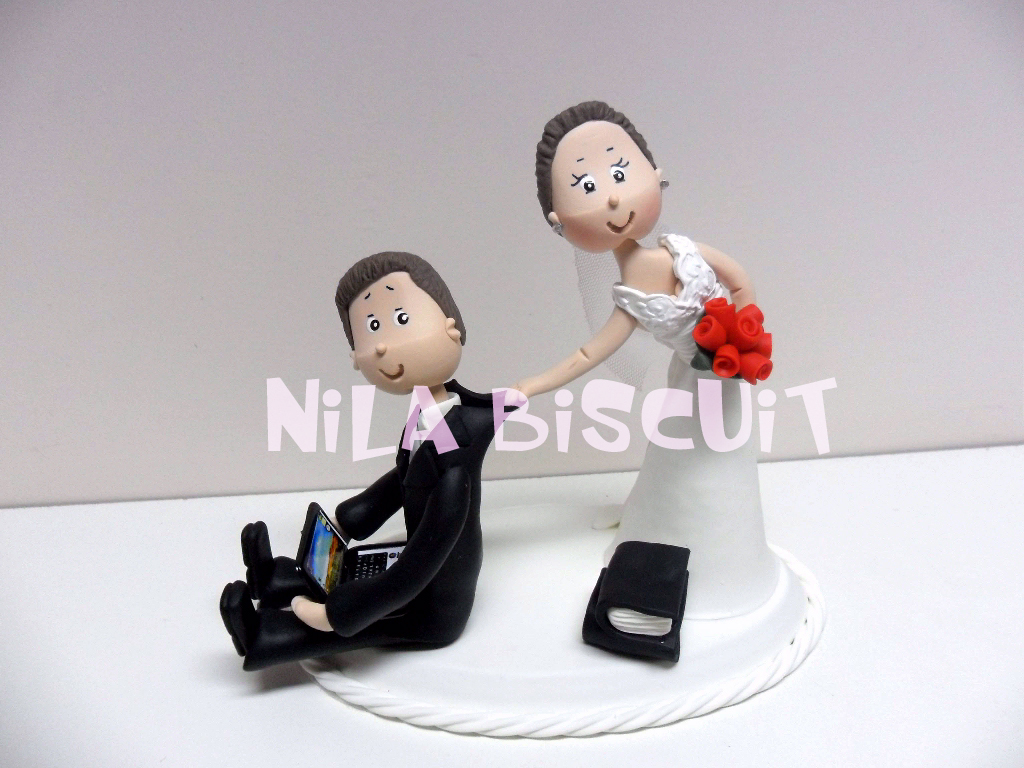 Bonequinhos do bolo de casamento com o noivo segurando notebook