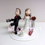 Bonequinhos do bolo de casamento, noivo quer jogar futebol e noiva segura ele pelo colarinho