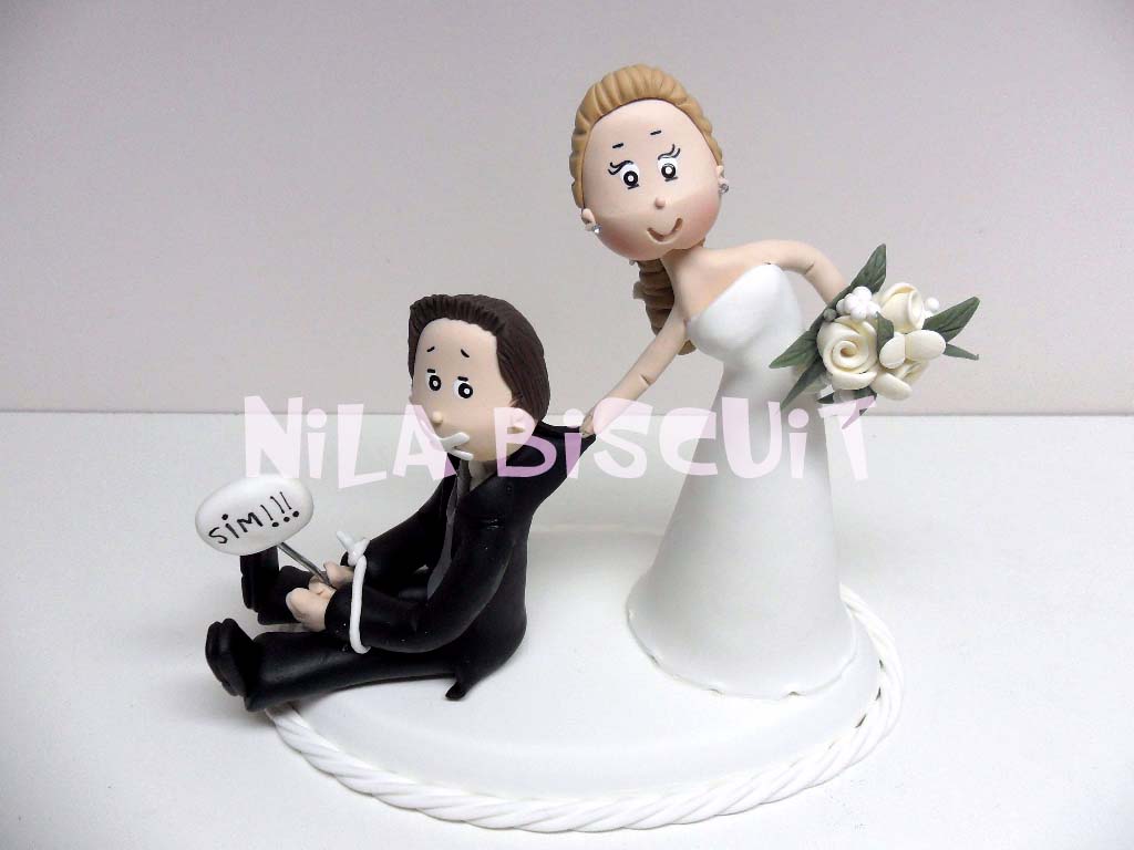 Noivinhos do bolo com o noivo amarrado sendo obrigado a casar
