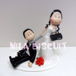 Noivinhos do bolo de casamento com a noiva puxando pela gravata